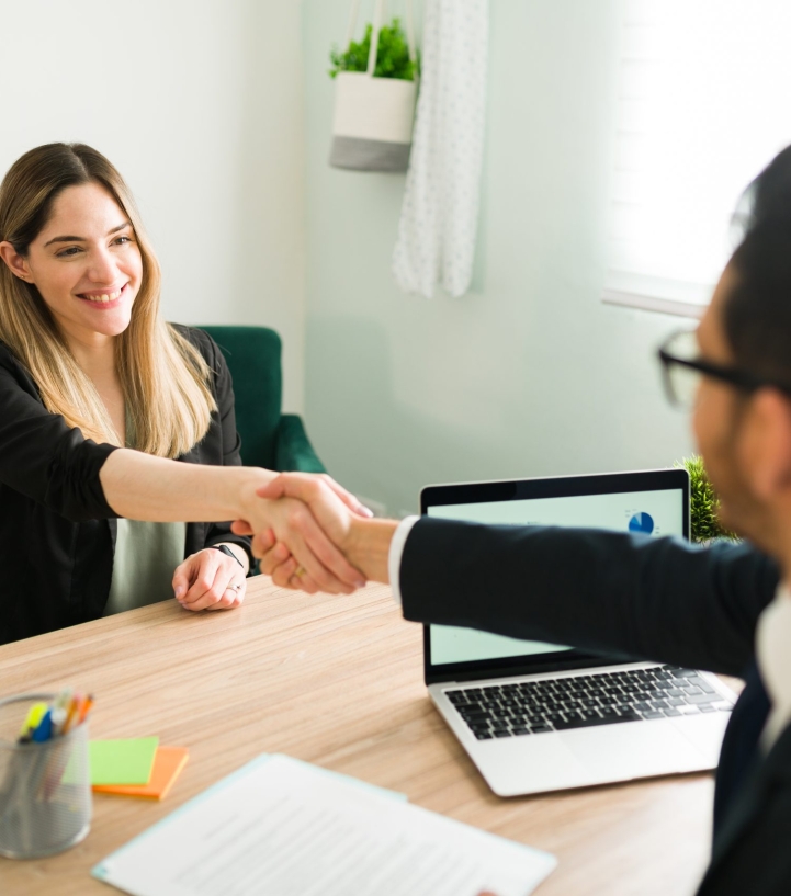 Happy caucasian woman shaking hands with a latin man during a business meeting with a lawyer. Manager hiring a beautiful professional woman for a new job